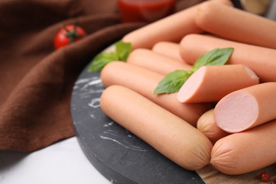 Photo of Delicious boiled sausages and basil on table, closeup