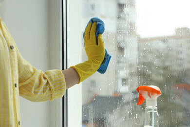 Photo of Woman cleaning window at home, closeup view