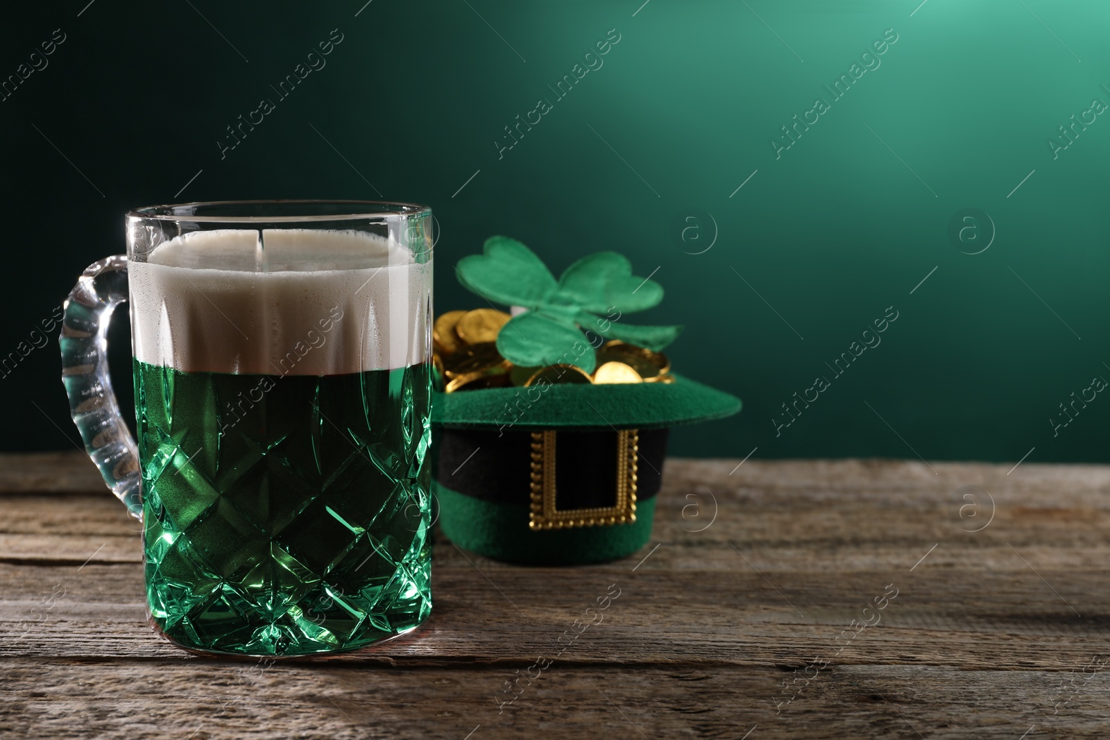 Photo of St. Patrick's day celebration. Green beer, leprechaun hat with gold and decorative clover leaf on wooden table. Space for text