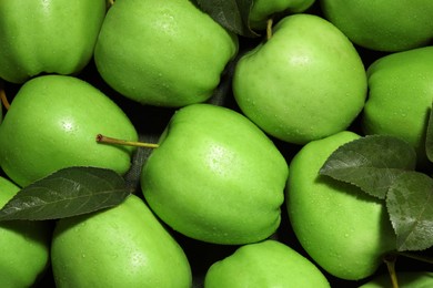 Photo of Fresh green apples and leaves with water drops on dark cloth, top view