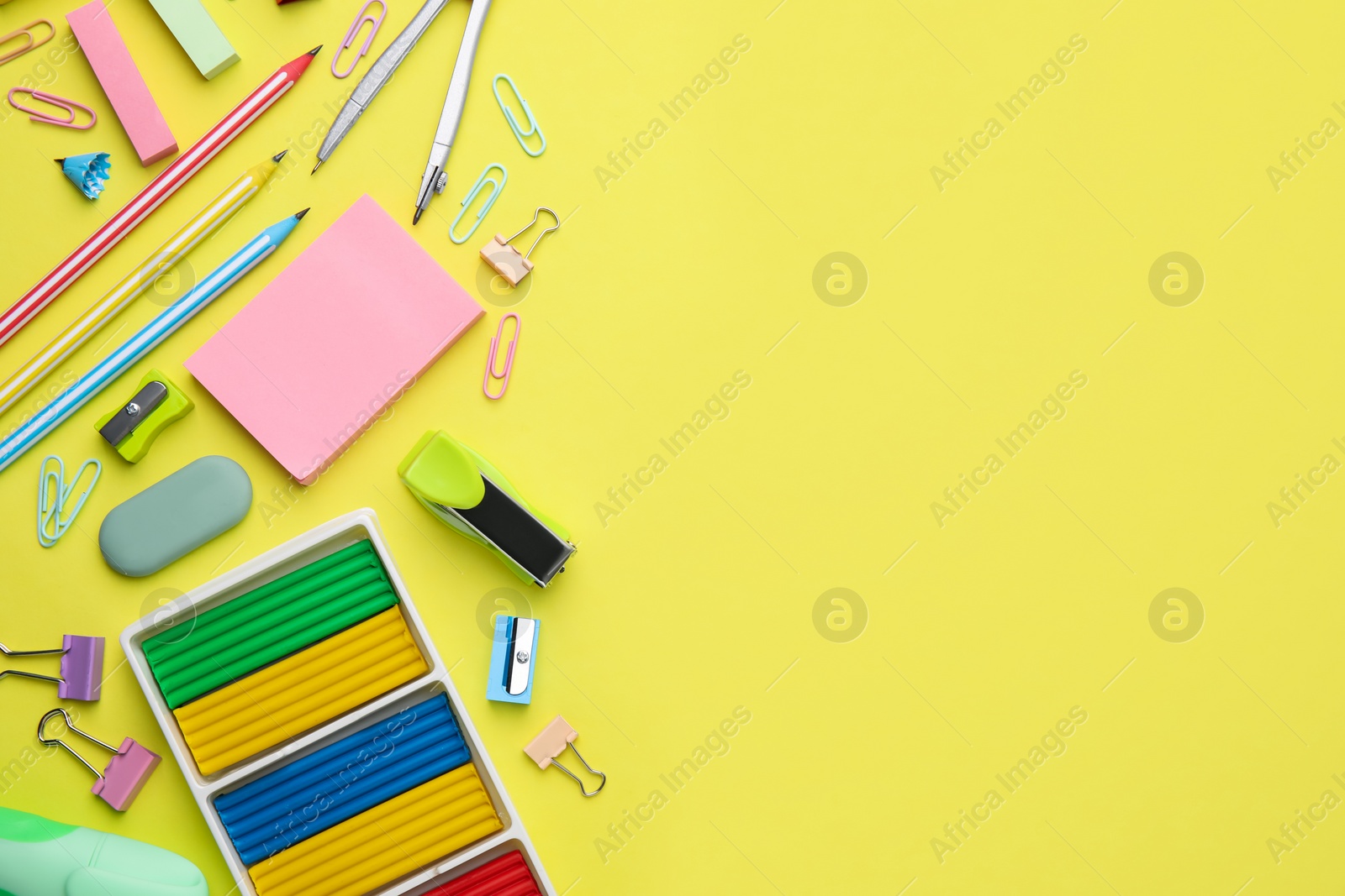 Photo of Flat lay composition with different school stationery on pale yellow background, space for text. Back to school