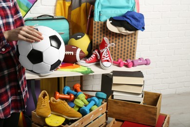 Photo of Woman holding ball near many different stuff indoors, closeup. Garage sale