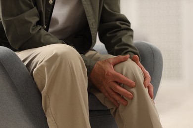 Photo of Senior man suffering from knee pain indoors, closeup. Rheumatism symptom