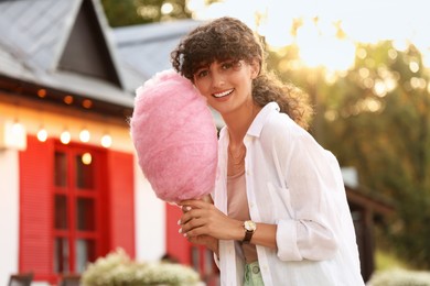 Photo of Smiling young woman with cotton candy outdoors