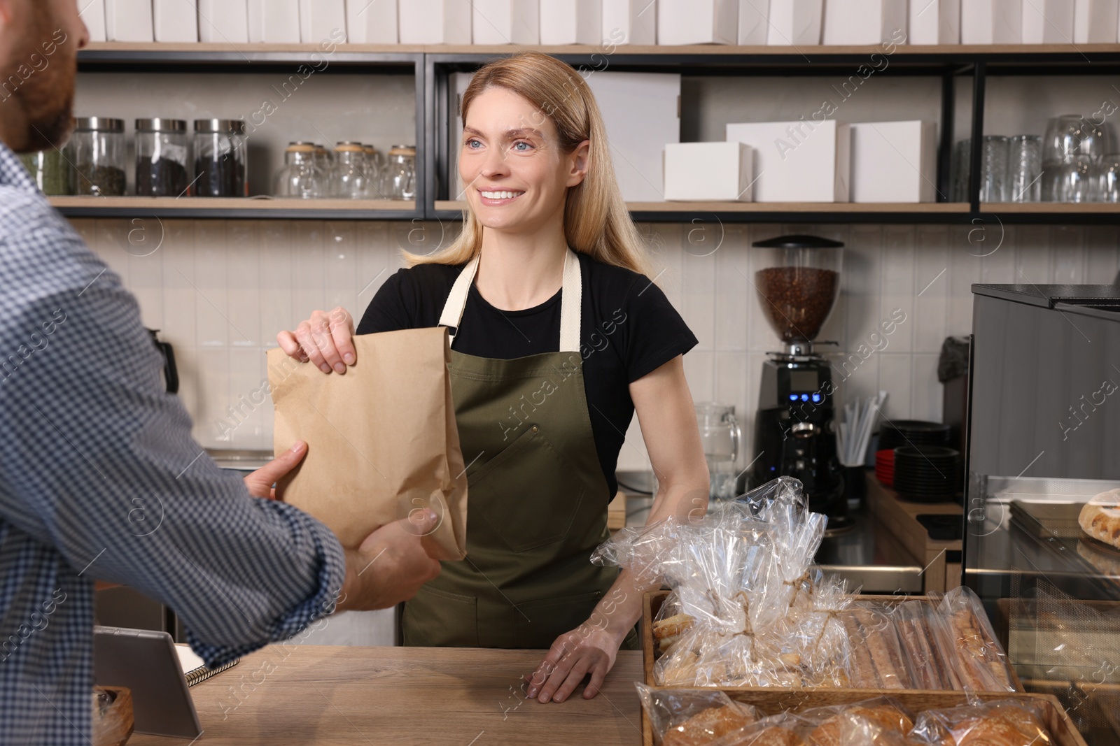 Photo of Seller giving customer fresh pastries in bakery shop