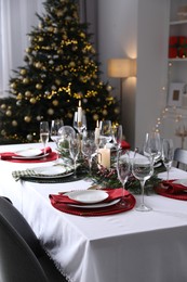 Christmas table setting with festive decor and dishware in room