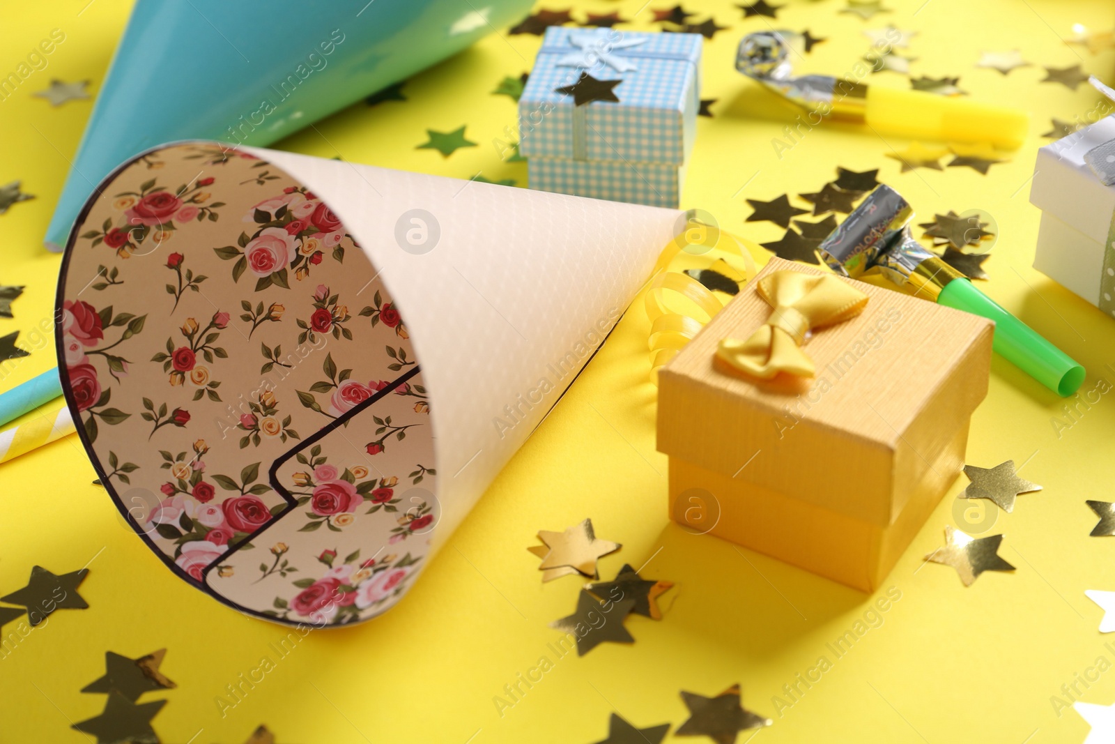 Photo of Party hats and other bright decor elements on yellow background