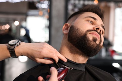 Professional hairdresser working with client in barbershop