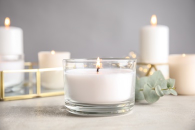 Photo of Burning aromatic candle and eucalyptus branch on table