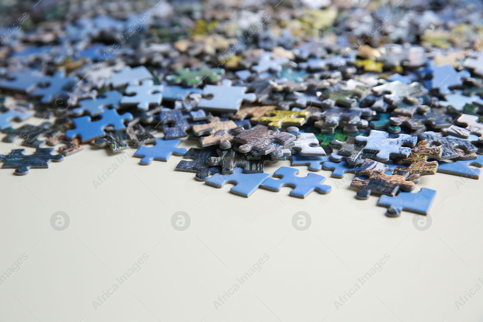 Photo of Puzzle pieces on white table, closeup view