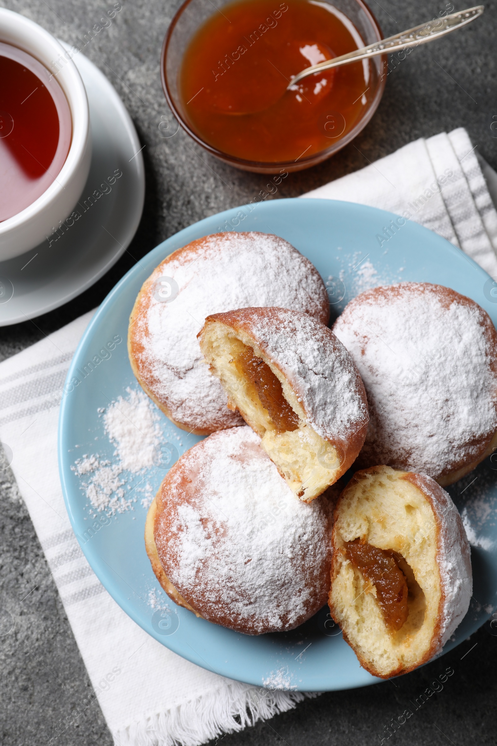 Photo of Delicious sweet buns with jam and cup of tea on table, flat lay