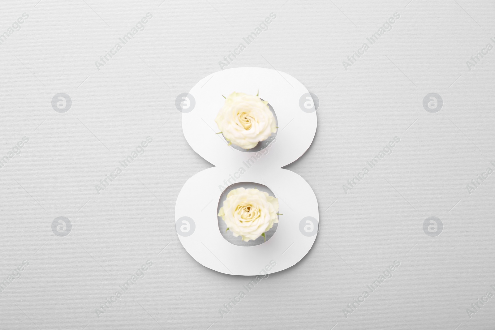 Photo of Paper number 8 and beautiful flowers on light grey background, top view