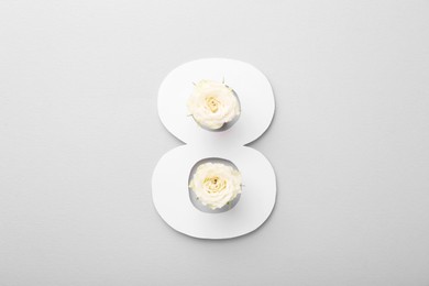 Photo of Paper number 8 and beautiful flowers on light grey background, top view