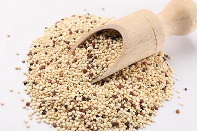 Photo of Scoop with raw quinoa seeds on white table, closeup