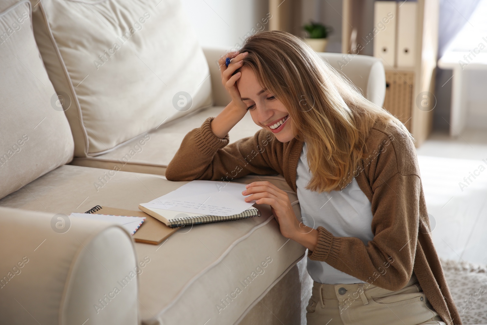 Photo of Happy woman writing letter on sofa at home