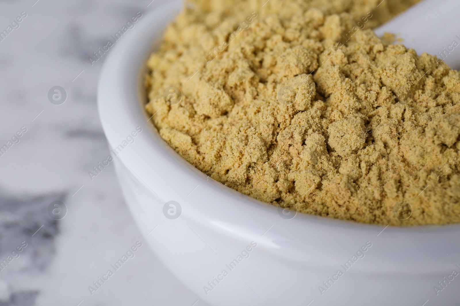 Photo of Mortar with aromatic mustard powder on white marble table, closeup