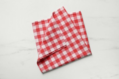 Red checkered tablecloth on white marble table, top view