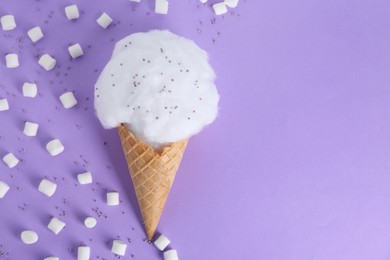 Sweet cotton candy in waffle cone and marshmallows on purple background, flat lay. Space for text