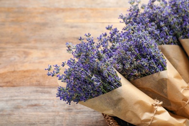 Fresh lavender flowers in basket on wooden table, closeup. Space for text