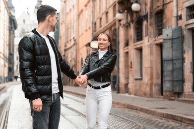 Photo of Lovely young couple walking along tram track on pavement road. Romantic date