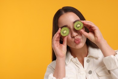 Photo of Woman covering eyes with halves of kiwi on yellow background, space for text