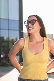 Photo of Beautiful smiling woman in sunglasses on city street, space for text