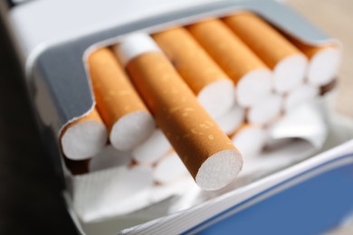 Photo of Cigarettes with orange filters in paper pack, closeup