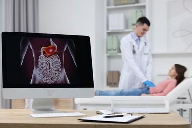 Photo of Gastroenterologist examining girl in clinic, focus on computer with image of digestive tract on table