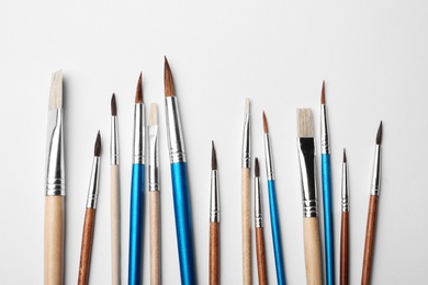 Photo of Different paint brushes on white background, top view