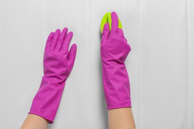 Photo of Woman in purple gloves cleaning white mattress with brush, top view