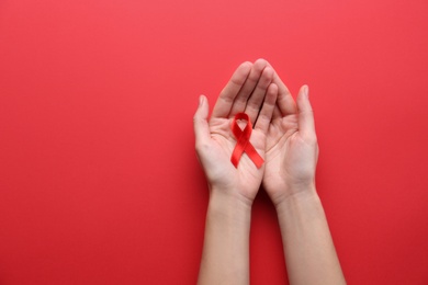 Photo of Woman holding red awareness ribbon on color background, top view with space for text. World AIDS disease day