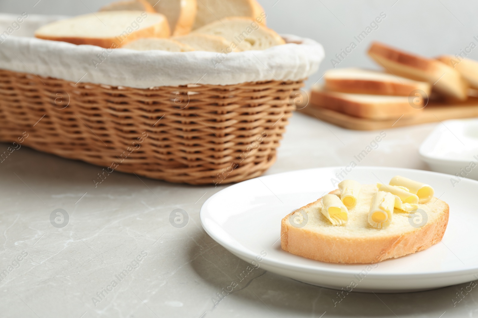 Photo of Slice of tasty fresh bread with butter on light marble table