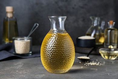 Photo of Fresh sesame oil in glass bottle on grey table