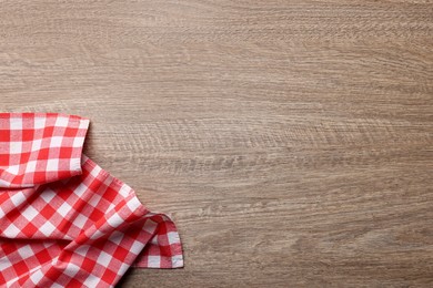 Checkered tablecloth on wooden table, top view. Space for text