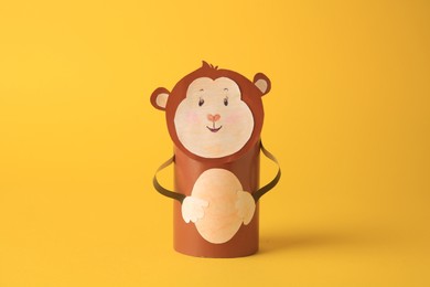 Toy monkey made from toilet paper hub on yellow background. Children's handmade ideas