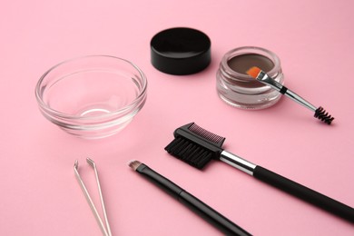 Eyebrow pomade with henna effect and professional tools on pink background