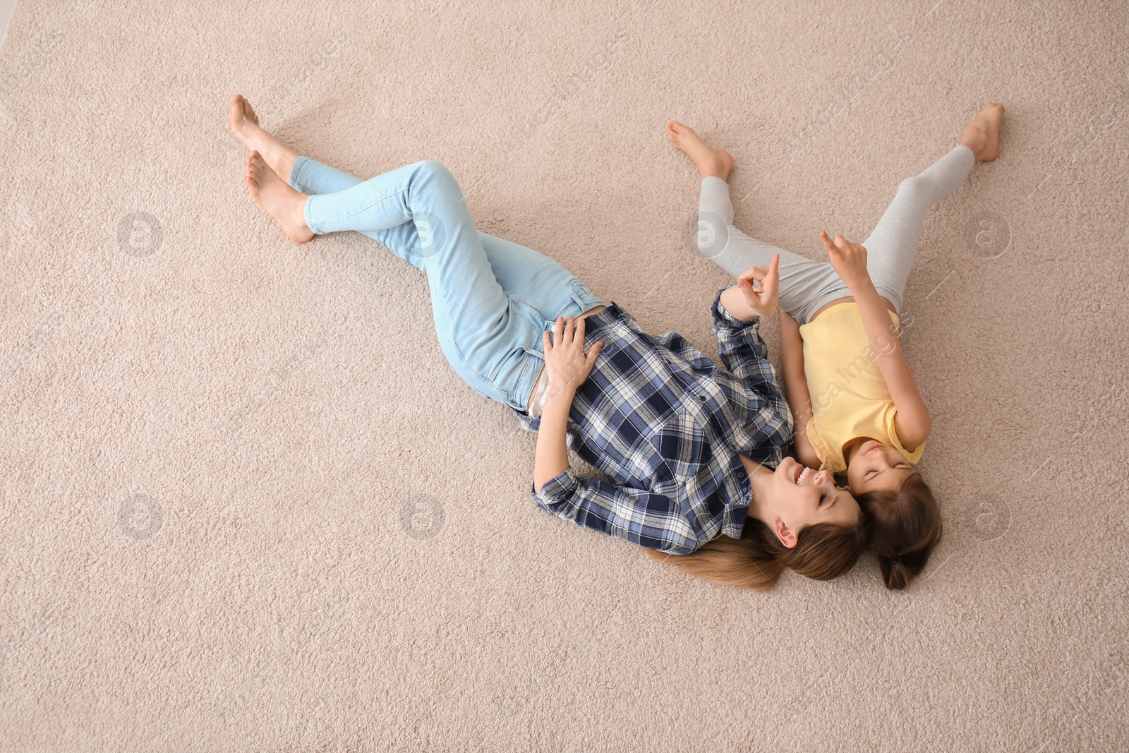 Photo of Cute little girl and her mother lying on cozy carpet at home