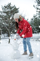 Young woman making snowman outdoors on winter day