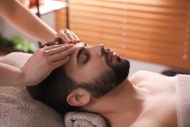 Photo of Young man receiving facial massage in beauty salon