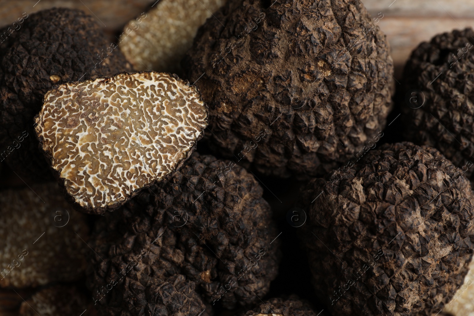 Photo of Heap of whole and cut black truffles, closeup