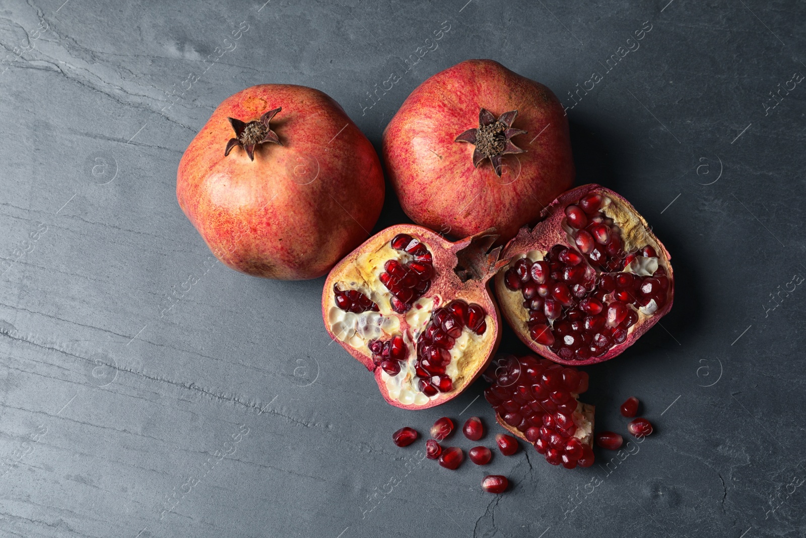 Photo of Ripe juicy pomegranates on grey background, top view