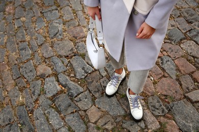 Photo of Stylish woman with trendy white baguette bag on city street, closeup