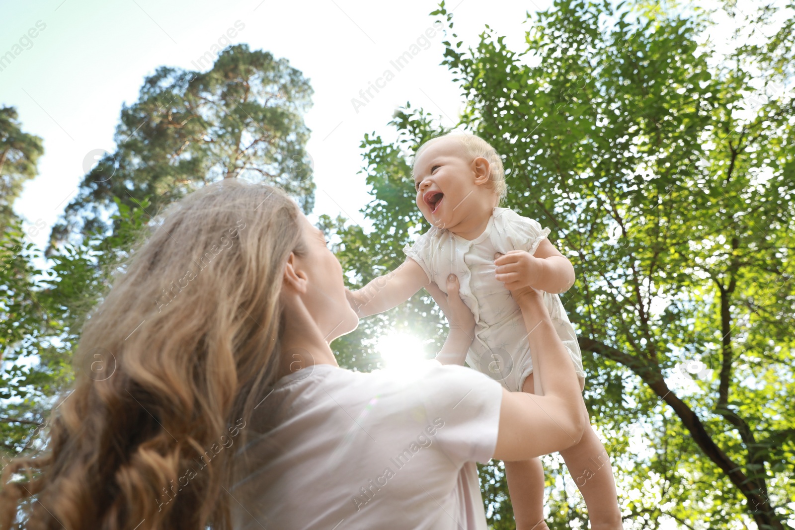 Photo of Mother with her cute baby spending time together outdoors, low angle view