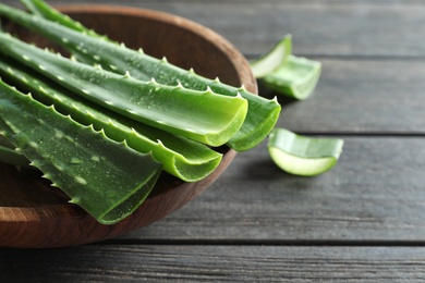 Bowl with fresh aloe vera leaves on wooden table