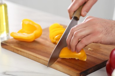 Closeup of chef cutting bell pepper at marble table, selective focus