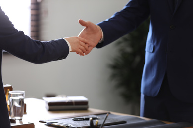 Male lawyer shaking hands with client in office, closeup