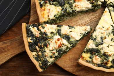 Delicious homemade spinach quiche on wooden board, closeup