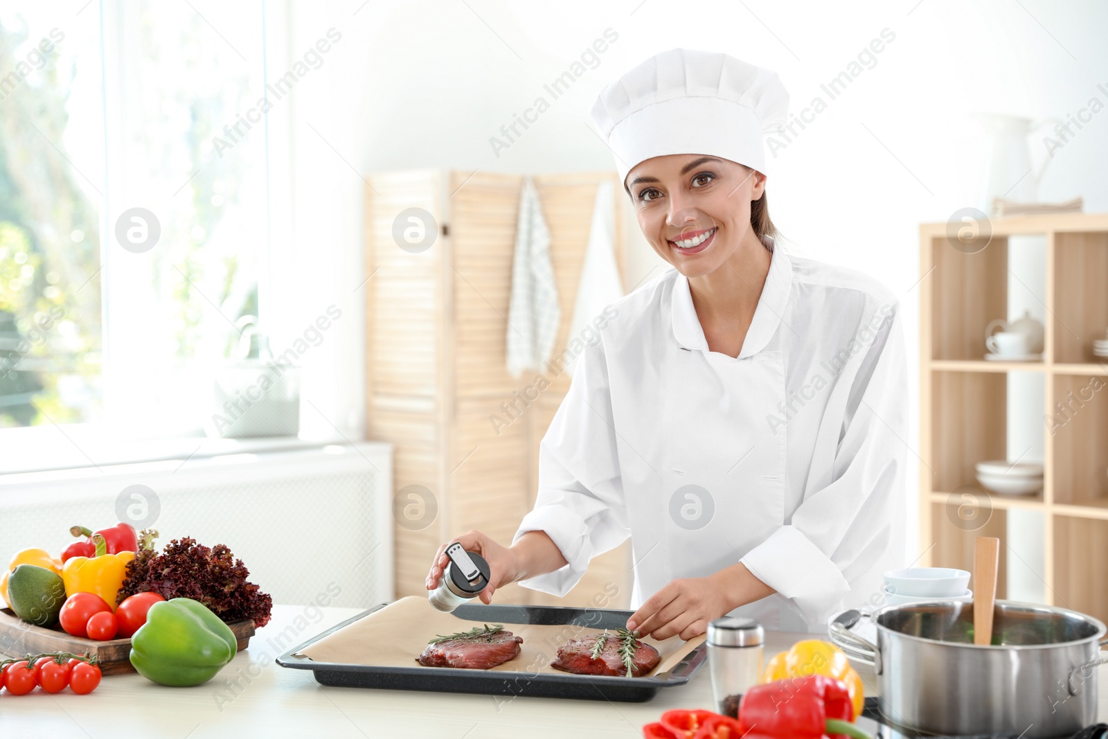 Photo of Professional female chef preparing meat on table in kitchen