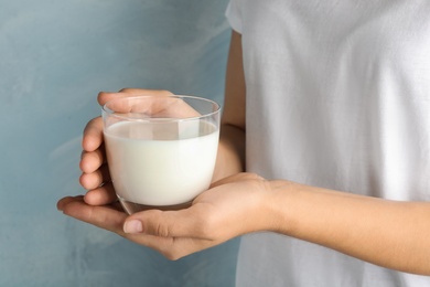 Photo of Woman holding glass of hemp milk on light blue background, closeup