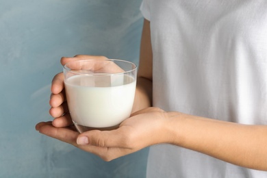 Woman holding glass of hemp milk on light blue background, closeup